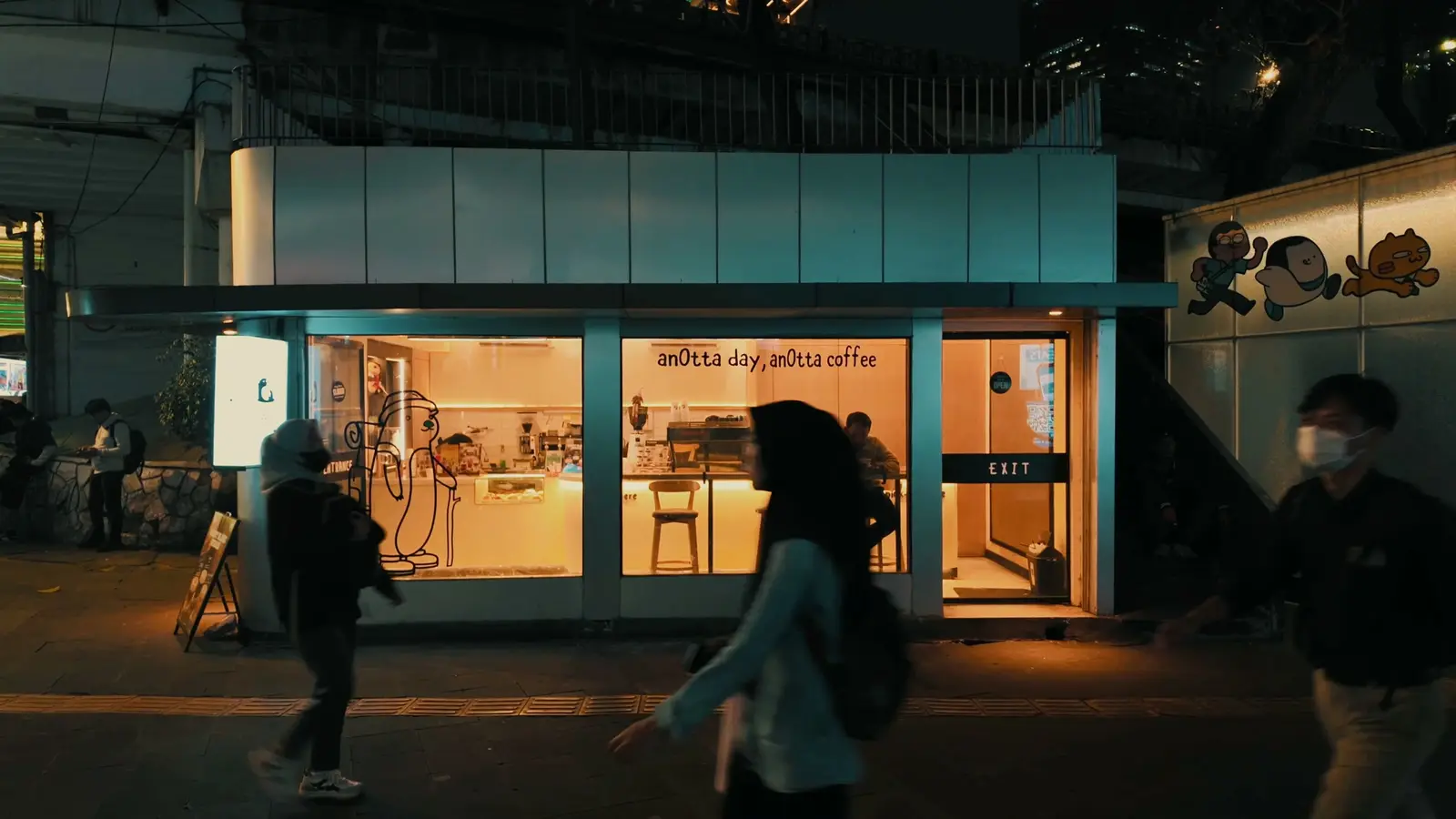 A corner café and passers-by at night